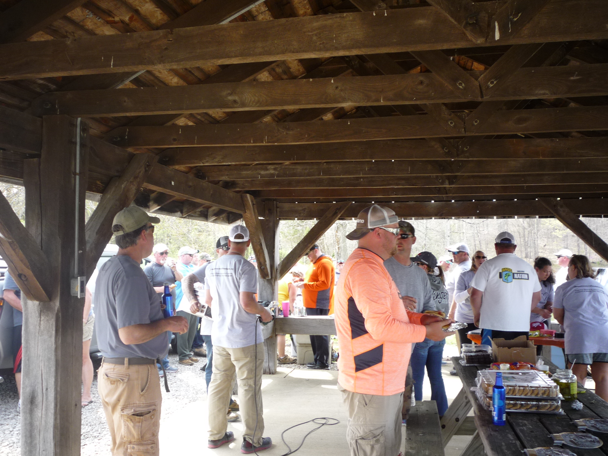 Gathering of people around picnic tables at bass tournament.