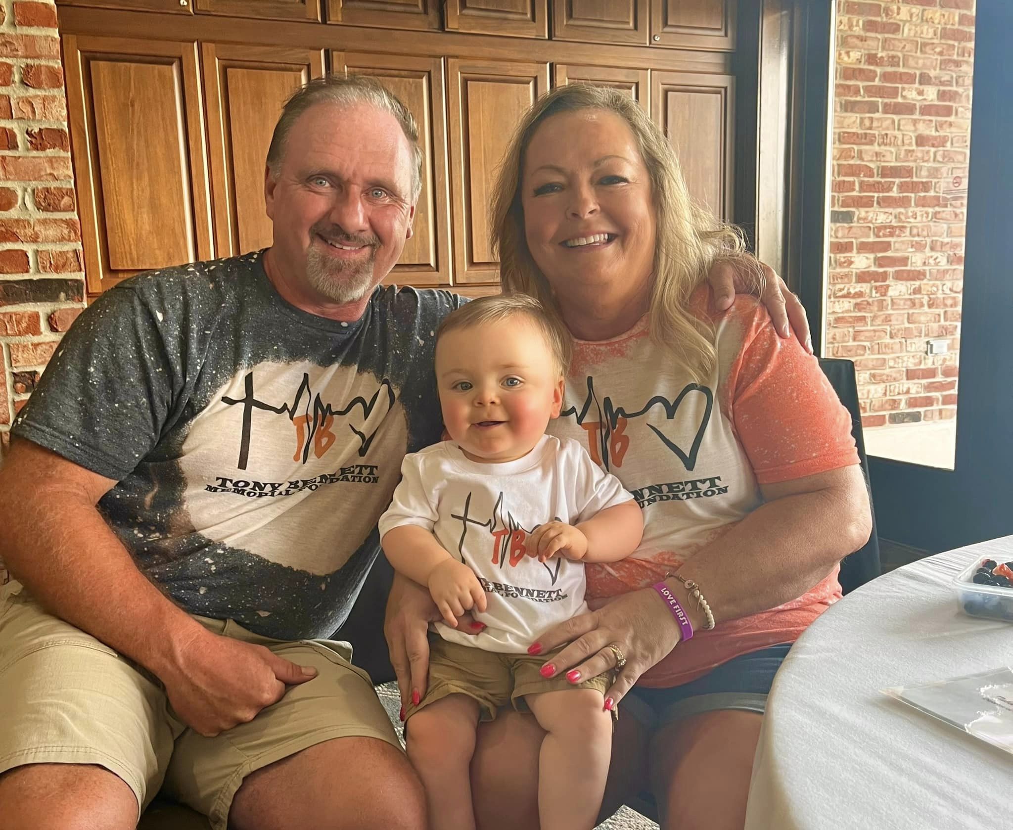 A family sitting together in TB Memorial shirts and smiling at the camera.