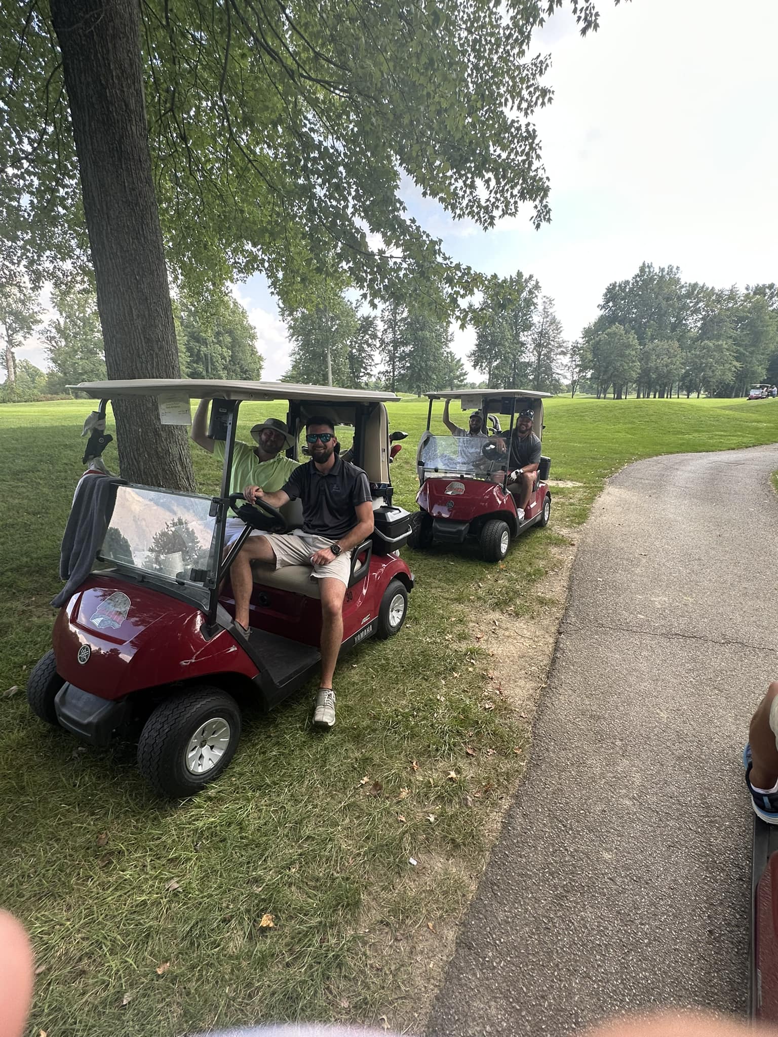 Two golfers sitting in a golf cart smiling at the camera.