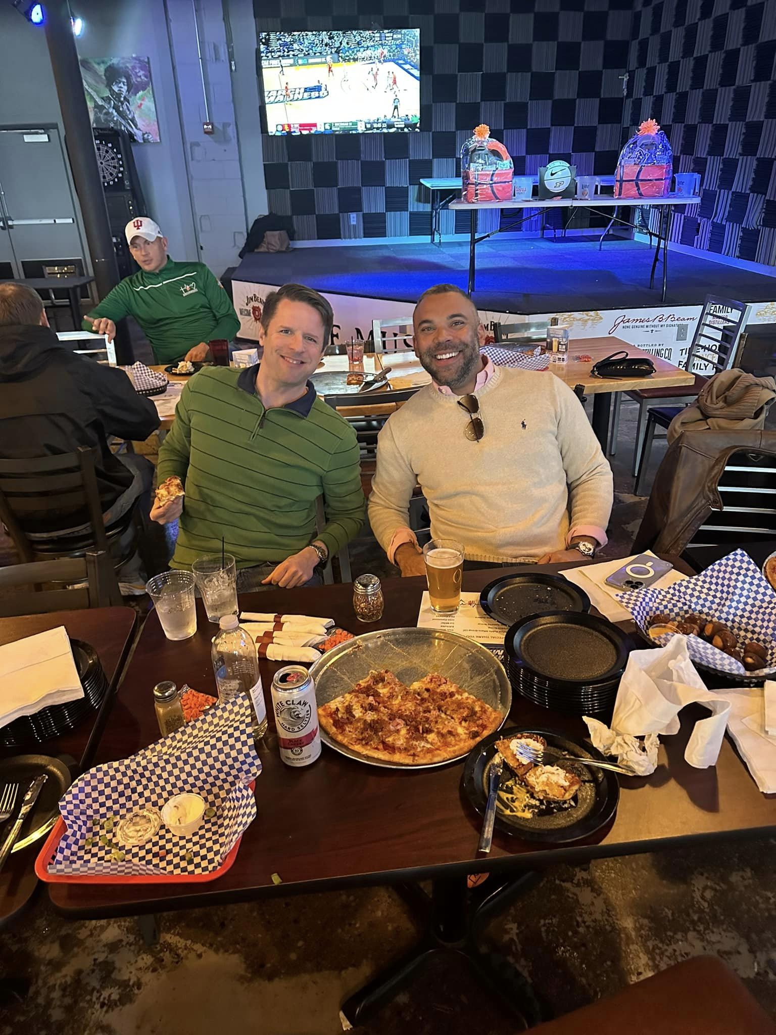 Two men eating pizza and smiling at the camera
