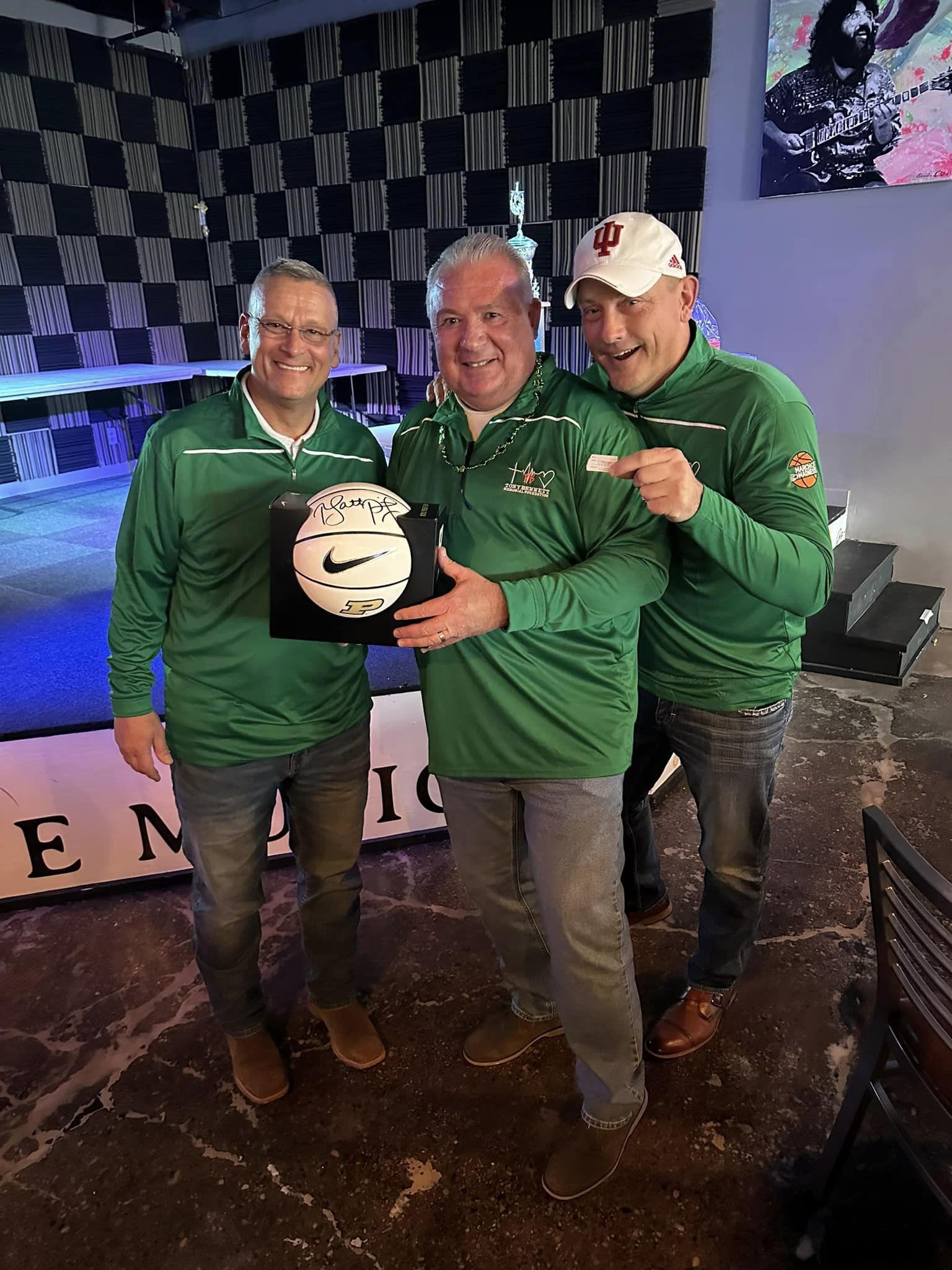 Three men posing with a basketball that was given away as a prize