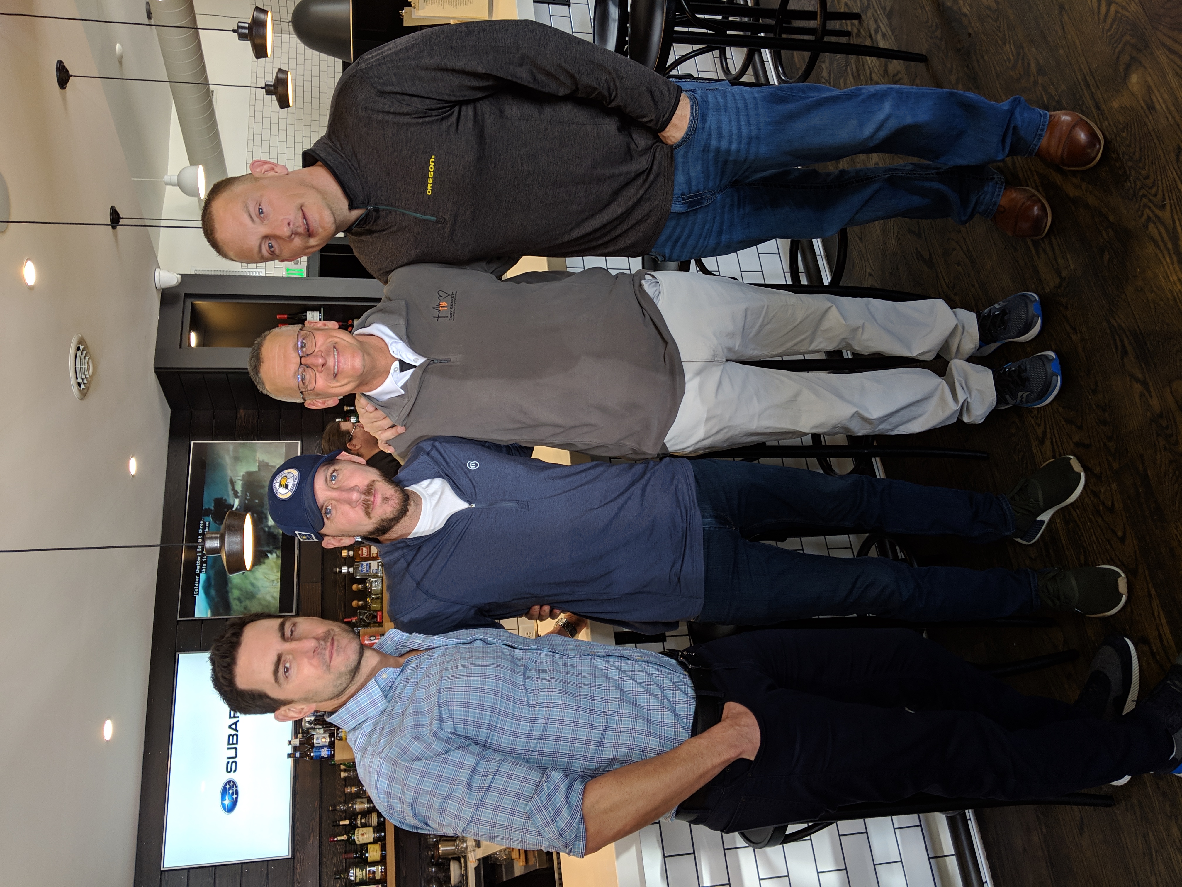 Four men posing for a picture at March Madness event.